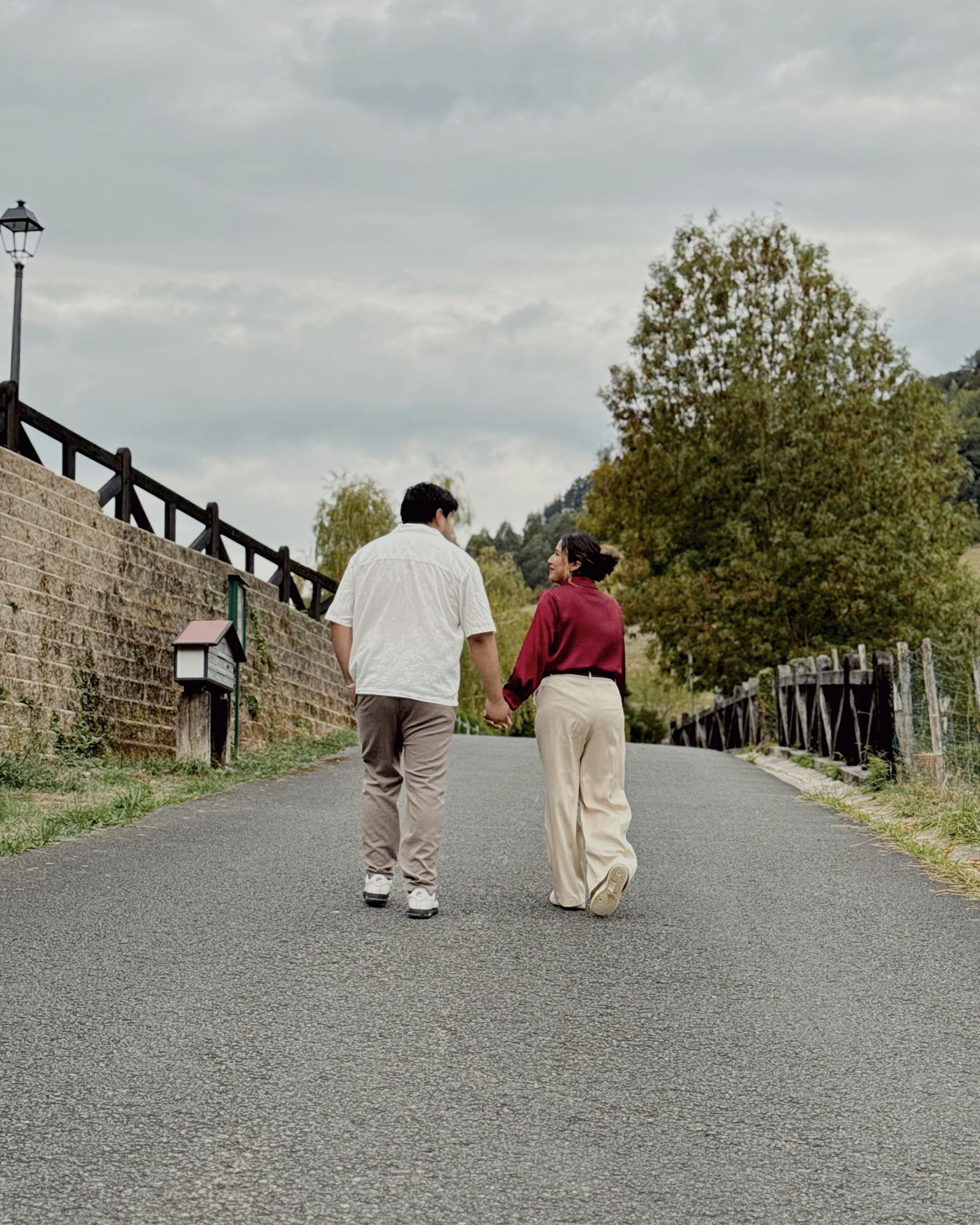 La pareja paseando de la mano por un camino entre montes